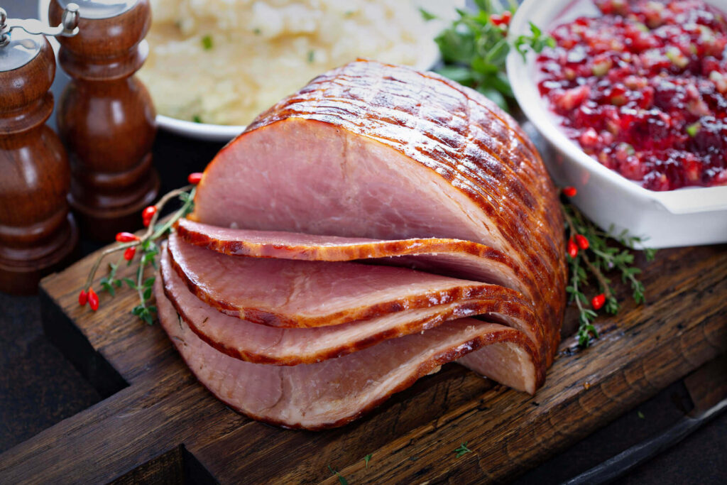 Heller recipe for how to glaze a ham. displayed on a wooden board with cranberry sauce